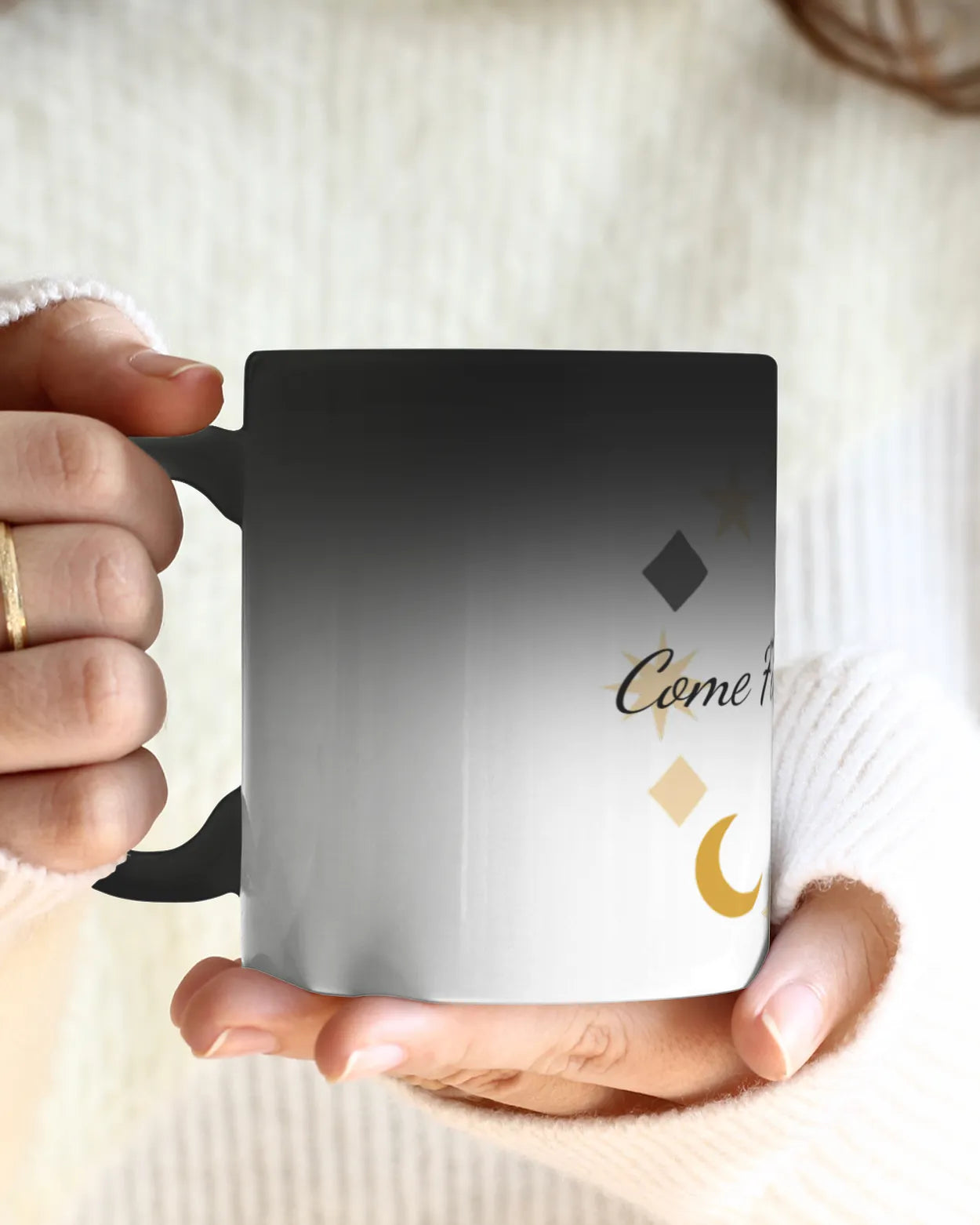Person holding a mug with decorative text and symbols on a light background